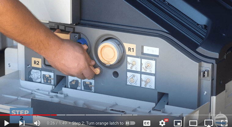 Printer technician turns the orange latch to the left on the Xerox AltaLink B8090 Printer