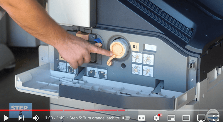 Printer technician turns the orange latch to the right on the Xerox AltaLink B8090 Printer